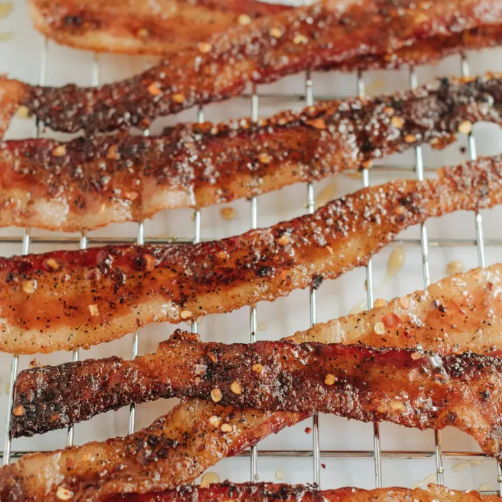 Candied bacon featuring pepper flakes and maple syrup on a baking rack