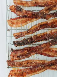 Crispy candied bacon with red pepper flakes on a baking rack