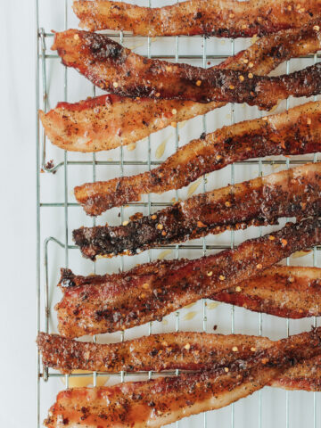 Crispy candied bacon with red pepper flakes on a baking rack