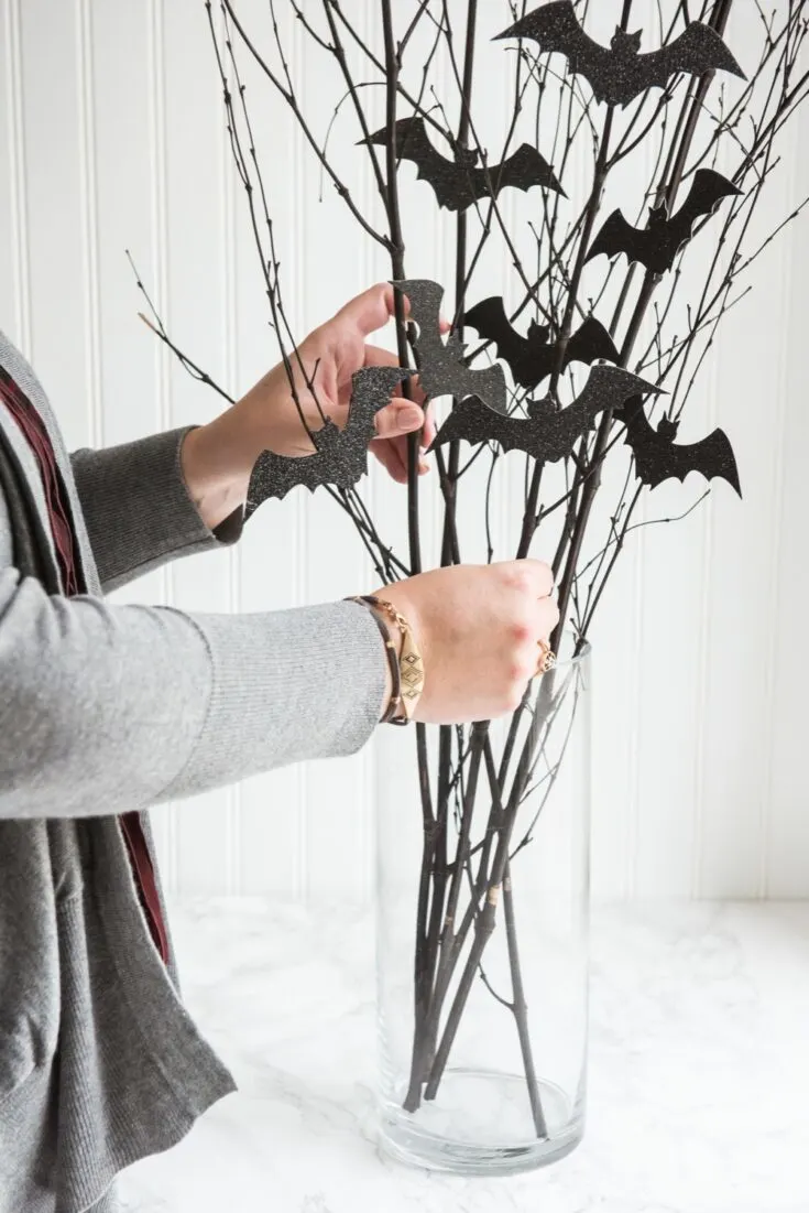 glass vase with branches with fake bats as decoration